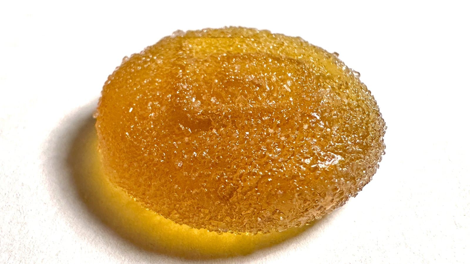 A single sugar-coated amber gummy on a white background